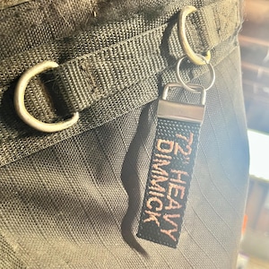 May include: A black key chain with a silver ring and a black tag that says "1/2" HEAVY DIMMICK" in pink thread.