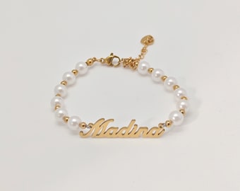 May include: Gold bracelet with white pearl beads and the name "Madina" engraved on it.