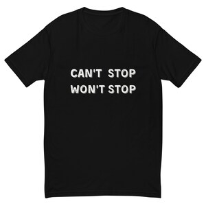 Puede incluir: Camiseta negra con el texto blanco "CAN'T STOP WON'T STOP" en una fuente negrita sin serifa. La camiseta tiene mangas cortas y cuello redondo. El texto está centrado en la parte delantera de la camiseta.