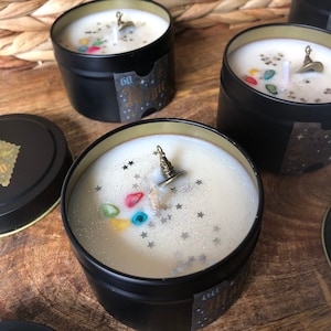 May include: Several black tin candles with white wax, each adorned with a miniature wizard hat charm, colorful gemstones, and silver glitter stars. The candles have a label that says "60 Magic".