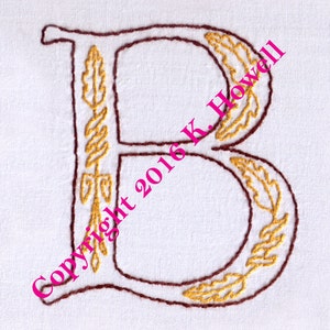 May include: Embroidered letter B with brown outline and gold leaf details. The letter is surrounded by a white background. Copyright 2016 K. Howell.