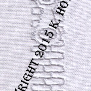 May include: White embroidery on a white fabric background, depicting a zipper design. The text "COPYRIGHT 2015 K. HOWELL" is diagonally across the image.