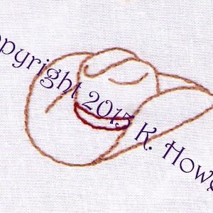 May include: A brown embroidered design of a cowboy hat on a white fabric background. The text "Copyright 2015 K. Howell" is embroidered in purple below the hat.