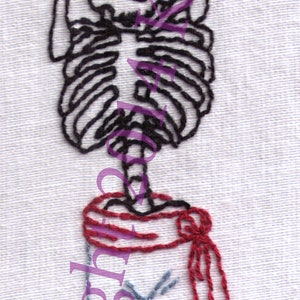 Könnte beinhalten: Gestickte Kunst mit einer Skelettfigur mit Schädel, Brustkorb und Beinen. Das Skelett trägt eine rote Schärpe und blaue Hosen. Das Kunstwerk ist auf weißem Stoff gestickt.