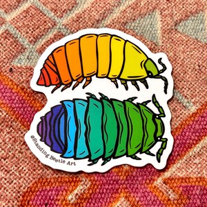 May include: Two colorful stickers featuring stylized beetle illustrations. One beetle transitions from red to yellow, the other from purple to green. The text "@Standing Beetle Art" is printed on the bottom sticker.