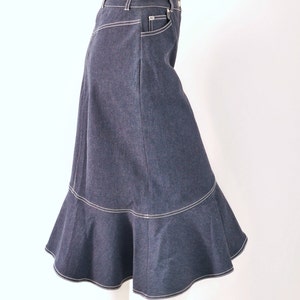 May include: A dark blue denim skirt with a ruffled hem and white stitching. The skirt has a high waist and a fitted silhouette.