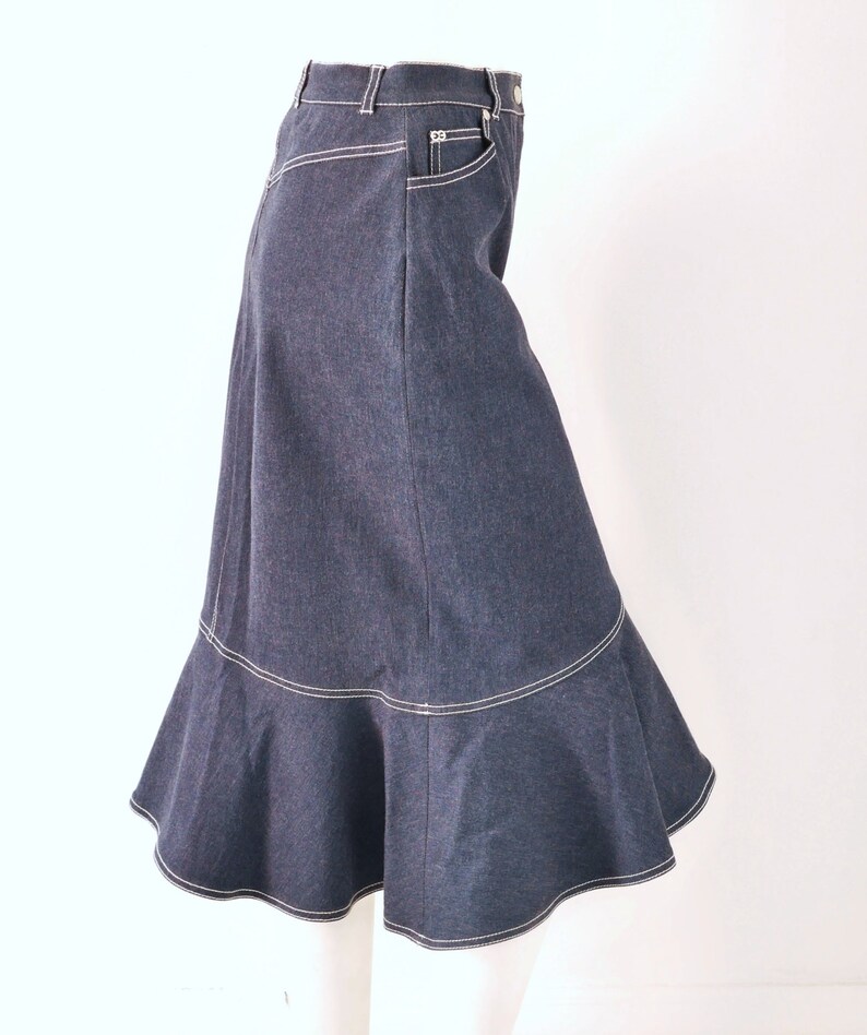 May include: A dark blue denim skirt with a ruffled hem and white stitching. The skirt has a high waist and a fitted silhouette.