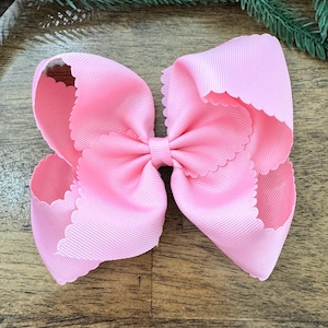 Può includere: Un grande fiocco per capelli rosa chiaro con un bordo smerlato. Il fiocco è realizzato in tessuto a coste e presenta un fiocco più piccolo al centro. Questo accessorio è perfetto per aggiungere un tocco di colore a qualsiasi acconciatura.