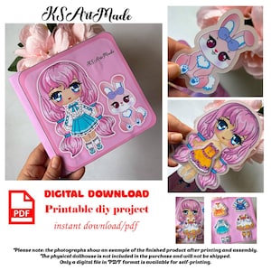 以下が含まれることがあります： ピンク色の、漫画の女の子とウサギのデザインの、印刷可能なDIYドールハウスプロジェクト。画像にはPDFアイコンと「デジタルダウンロード、印刷可能なDIYプロジェクト、インスタントダウンロード/pdf」というテキストが含まれています。完成品の例も表示されています。