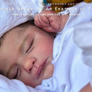 Może przedstawiać: Zbliżenie śpiącego dziecka w białym kapturze i kocu. Dziecko ma zamknięte oczy i zaróżowione policzki. Obraz zawiera tekst: "This Image Shown As An Example of The Kit".