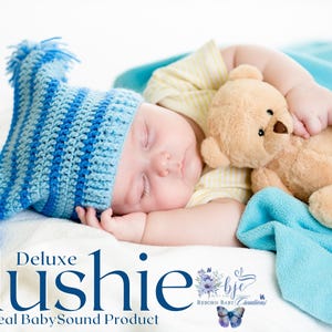 Può includere: Un bambino che dorme con un cappello all'uncinetto a righe blu e bianche e che tiene in mano un piccolo orsacchiotto marrone. Il bambino è sdraiato su una coperta bianca con una coperta blu sullo sfondo. Il testo sull'immagine recita "Deluxe Plushie, A Real Baby Sound Product."