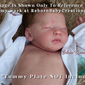 Może przedstawiać: Realistyczna lalka reborn z zamkniętymi oczami, ubrana w białe body. Lalka ma smoczek i leży na teksturowanej, brązowej powierzchni. Tekst na zdjęciu brzmi "This Image Is Shown Only To Reference The Kit" i "#01 *Tummy Plate NOT Included."