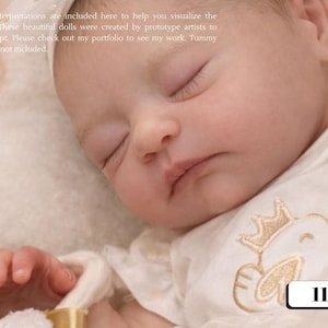 Może przedstawiać: Śpiące dziecko w białym body ze złotym haftowanym wzorem. Oczy dziecka są zamknięte, a skóra jasna. Obraz zawiera tekst "112-44".