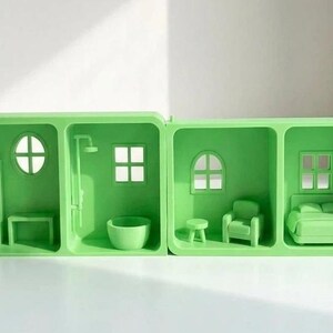 May include: A lime green miniature dollhouse with four rooms. The rooms include a bathroom with a shower and tub, a living room with a chair and table, and a bedroom with a bed. The dollhouse has a white cord.