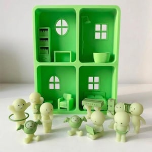 May include: A green dollhouse with four rooms, each with miniature furniture and windows. Several small, light green figurines are scattered around the dollhouse, some holding objects. The dollhouse and figurines are made of plastic.