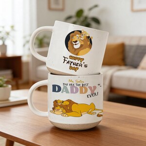 Könnte beinhalten: Zwei weiße Keramikbecher übereinander gestapelt. Der obere Becher hat eine Löwenillustration und den Text "HAPPY FATHER'S DAY". Der untere Becher hat eine Löwenillustration und den Text "Mr. Smith YOU ARE THE BEST DADDY EVER!"