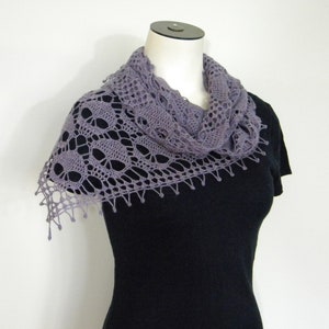 May include: A gray crocheted shawl with a delicate lace pattern. The shawl is draped over a black shirt.