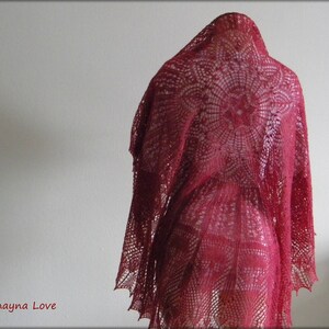 May include: A red crocheted shawl with a circular pattern. The shawl is draped over a mannequin.