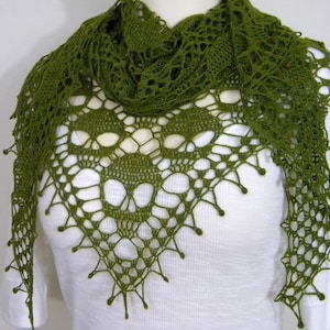 May include: A green crocheted shawl with a skull design. The shawl is made with a delicate lace pattern and has a fringed edge.