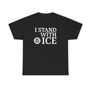 Könnte beinhalten: Schwarzes T-Shirt mit dem weißen Text "I STAND WITH ICE". Das Shirt zeigt auch ein rundes Emblem des Ministeriums für Innere Sicherheit. Das T-Shirt besteht aus einem weichen, bequemen Material.