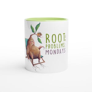 Può includere: Una tazza in ceramica bianca con un bordo verde. La tazza presenta un'illustrazione di cartone animato di una radice scontrosa con un uccello appollaiato su un ramo. Il testo "ROOT of all PROBLEMS: MONDAYS" è stampato sulla tazza.