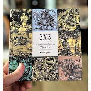 May include: A book titled "3x3: A Post-It Note Collection Volume One" by Kennon James. The cover features a colorful collage of nine illustrations, including a woman with horns, a creature with wings, a man eating a chicken leg, a van, a woman with horns and a crown, a creature with tentacles, a robot, and a dragon.
