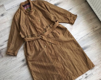 Puede incluir: Una gabardina larga de color marrón con mangas largas, cinturón y botones dorados.