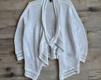 May include: White crochet cardigan with a draped open front and a scalloped trim.