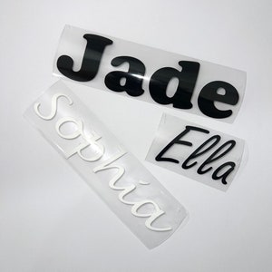 May include: Three name decals: "Jade" in black, "Sophia" in white, and "Ella" in black. The names are in a cursive font, each on a clear backing. Suitable for personalising items.