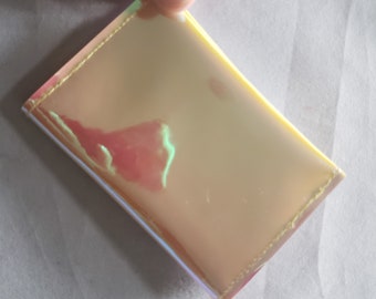 May include: A small, iridescent, gold-colored wallet with a white seam around the edges.
