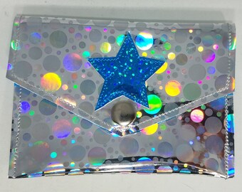 May include: A silver holographic wallet with a blue glitter star and a silver button closure. The wallet has a pattern of iridescent circles.