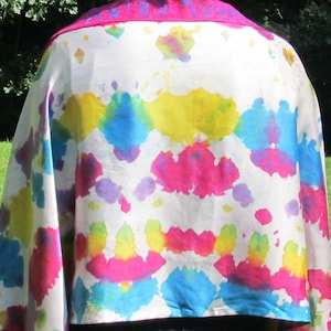 May include: A white silk shawl with a tie-dye pattern in shades of pink, blue, yellow, and purple. The shawl has a pink border.