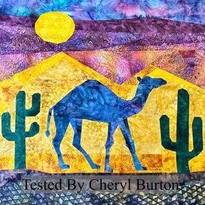 May include: A blue camel silhouette against a yellow desert landscape with two green cacti. The sky is a gradient of purple, blue, and yellow with a yellow sun. The text "Tested By Cheryl Burton" is at the bottom of the image.