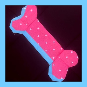 May include: A pink and blue dog bone shaped fabric with a white polka dot pattern.