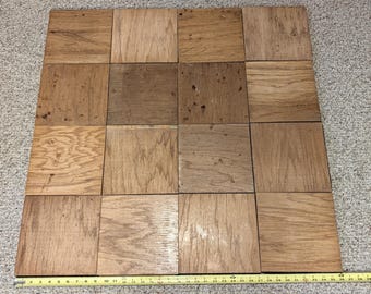 Puede incluir: Una cuadrícula de dieciséis baldosas de madera cuadradas dispuestas en cuatro filas y cuatro columnas. Cada baldosa presenta un patrón de veta de madera natural único en varios tonos marrones. Una cinta métrica amarilla se coloca a lo largo del borde inferior.