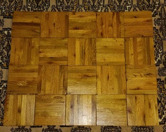 Puede incluir: Una disposición cuadrada de veinte baldosas de madera individuales, cada una con un patrón de veta natural distintivo en tonos marrón dorado. Las baldosas están dispuestas en una cuadrícula, mostrando las texturas variadas y los tonos cálidos de la madera.
