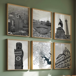 Può includere: Sei stampe in bianco e nero incorniciate di paesaggi urbani e monumenti sono appese a una parete verde. Le stampe includono un paesaggio urbano, uno stadio di baseball, un monumento, una torre dell'orologio, una mappa di Baltimora e un edificio.
