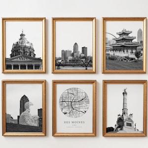 May include: A set of six black and white framed prints featuring landmarks and a map of Des Moines, Iowa. The collection includes the Iowa State Capitol, the city skyline, a pagoda, a sculpture, a circular street map, and a tall stone monument.