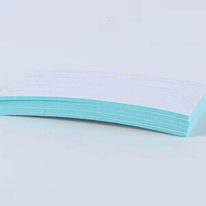 May include: A stack of white paper sheets with light blue edges, slightly curved. The paper is neatly stacked, creating a clean and organized appearance. The background is a solid, light blue color.