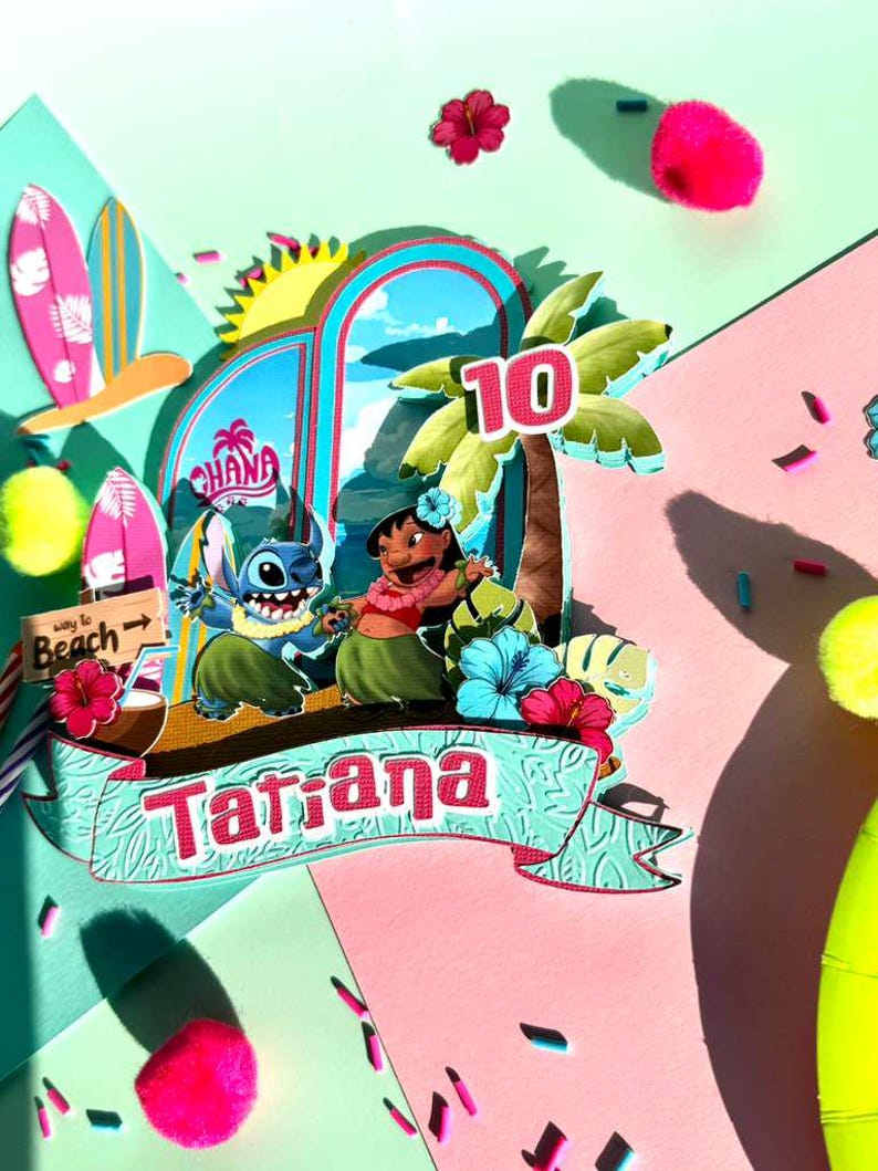 Puede incluir: Un adorno para tarta de cumplea&ntilde;os colorido con los personajes Stitch y Lilo de la pel&iacute;cula Lilo & Stitch. El adorno incluye una palmera, el n&uacute;mero 10 y el nombre "Tatiana" en una pancarta. Elementos decorativos: tablas de surf, flores y pompones.