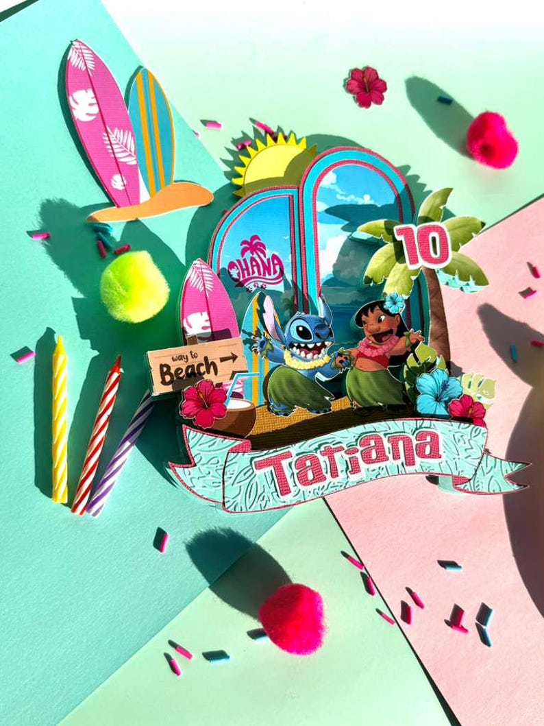 Puede incluir: Adorno de pastel de cumplea&ntilde;os colorido con tem&aacute;tica tropical con los personajes Stitch y Lilo. El dise&ntilde;o incluye tablas de surf, palmeras y el nombre "Tatiana" en una pancarta. Tambi&eacute;n se muestra el n&uacute;mero "10".