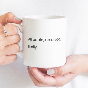 Könnte beinhalten: Eine weiße Keramiktasse mit dem Text "All panic, no disco, Emily" darauf.