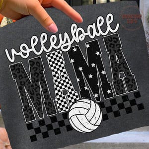 May include: Dark gray t-shirt with the words "Volleyball MAMA" in white script and block letters. The letter "M" features a checkered pattern, the "A"s have a leopard print, and the other letters have white stars. A volleyball graphic is at the bottom.