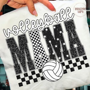 May include: White t-shirt with the words "Volleyball Mama" in a distressed font. The word "MAMA" features a checkered pattern, stars, and a leopard print design. A white volleyball is at the bottom, and the shirt is held by a hand.