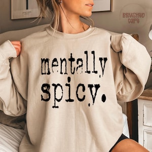 Puede incluir: Sudadera beige con la frase "mentally spicy" en negro, en negrita, con fuente de m&aacute;quina de escribir. La parte superior de manga larga est&aacute; hecha de un material suave y es adecuada para uso casual.