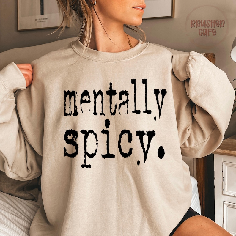 Puede incluir: Sudadera beige con la frase "mentally spicy" en negro, en negrita, con fuente de m&aacute;quina de escribir. La parte superior de manga larga est&aacute; hecha de un material suave y es adecuada para uso casual.