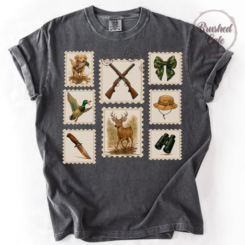 Peut inclure: T-shirt gris fonc&eacute; avec des motifs de timbres-poste sur le th&egrave;me de la chasse. Les timbres repr&eacute;sentent un chien de chasse, des fusils crois&eacute;s, un n&oelig;ud papillon, un chapeau, des jumelles, un couteau, un canard et un cerf. Le t-shirt a un aspect vintage.