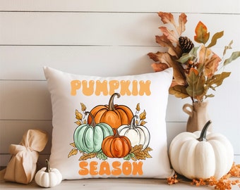 Puede incluir: Almohada blanca con un gráfico de calabazas y el texto "Pumpkin Season" en letras naranjas.