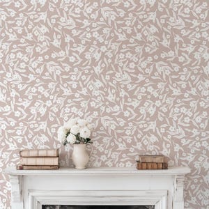 May include: A room with a floral wallpaper design in a neutral color palette. The wallpaper features a repeating pattern of white flowers and leaves on a light brown background. A white mantel holds a vase of white flowers and a stack of books.