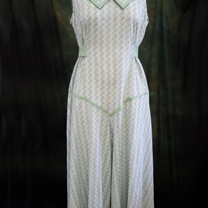 May include: A sleeveless dress with a green and white chevron pattern. The dress has a wide, green collar with a white trim and a green sash at the waist.